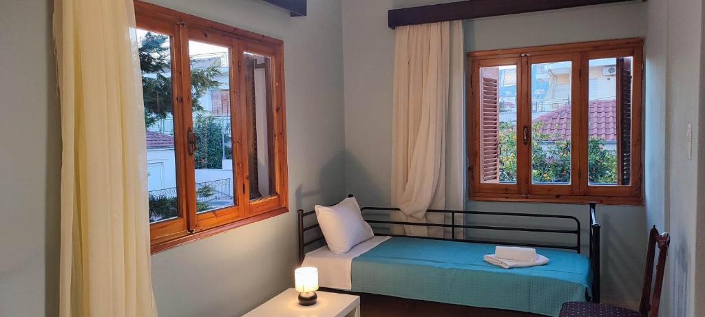 a small bedroom with a bed and two windows at Anchialos seafront appartement in Nea Anchialos