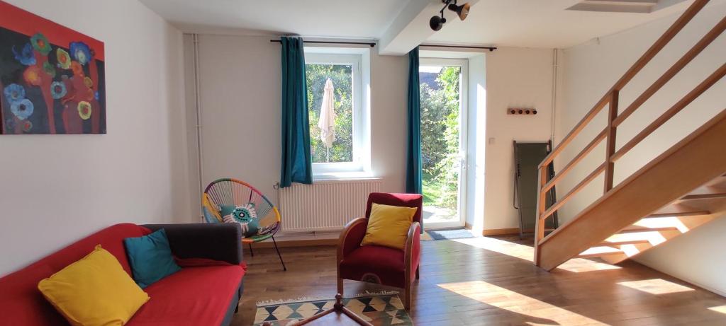 a living room with a red couch and two chairs at Le nid d'Eugénie in Blaudeix