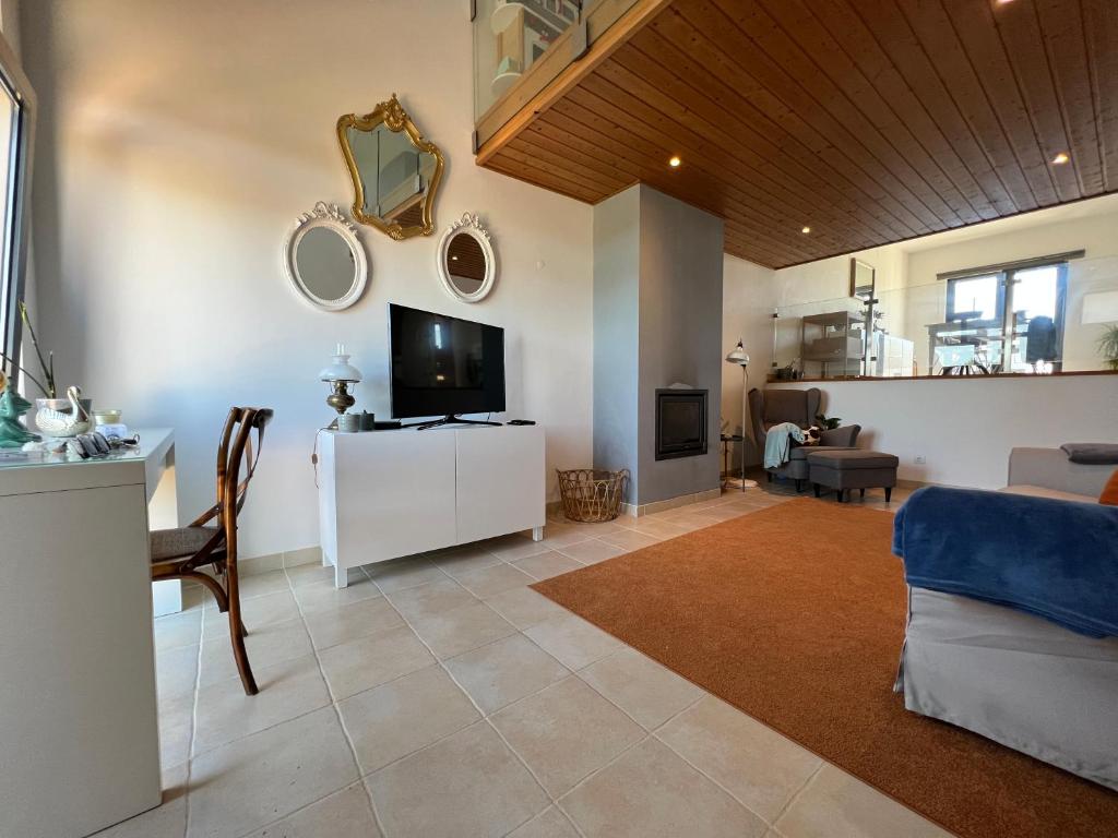 a living room with a tv and a couch and a table at Casa Parreira Raposeira, Algarve in Raposeira