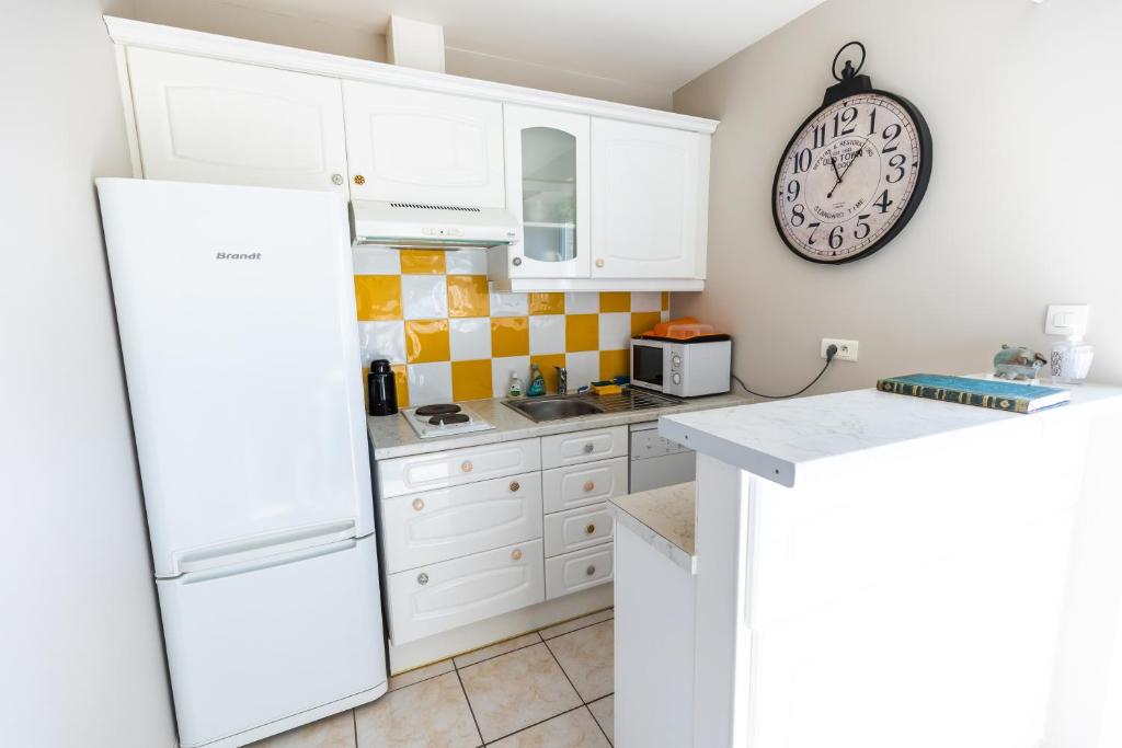 a kitchen with white cabinets and a clock on the wall at La Minoterie in Tessy-sur-Vire