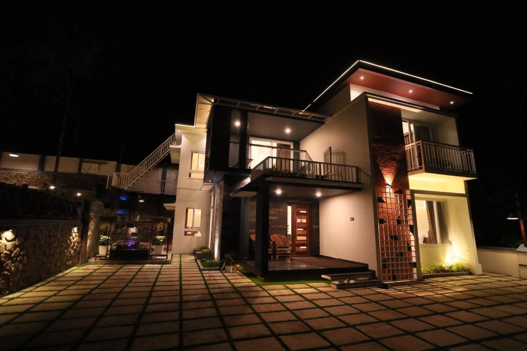a large white house with a courtyard at night at DIGA VISTA LAKE VIEW COTTAGE in Munnar