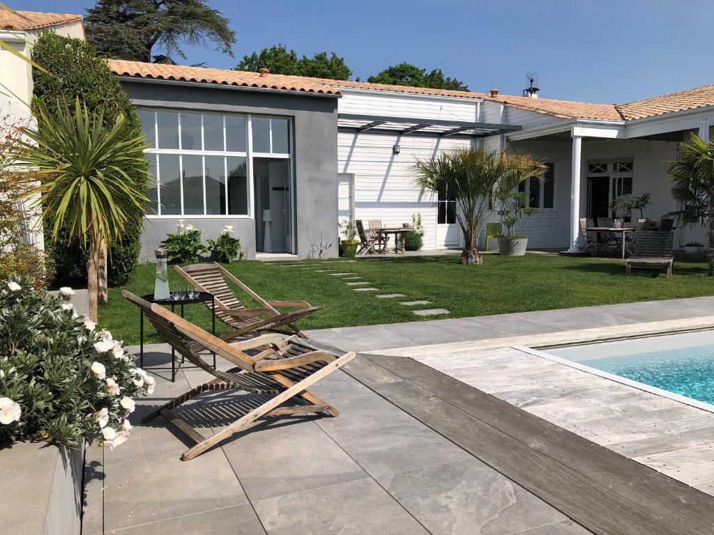 a backyard with two lounge chairs and a swimming pool at Maison M, chambre privée accès jardin piscine et jacuzzi près de La Rochelle in La Rochelle