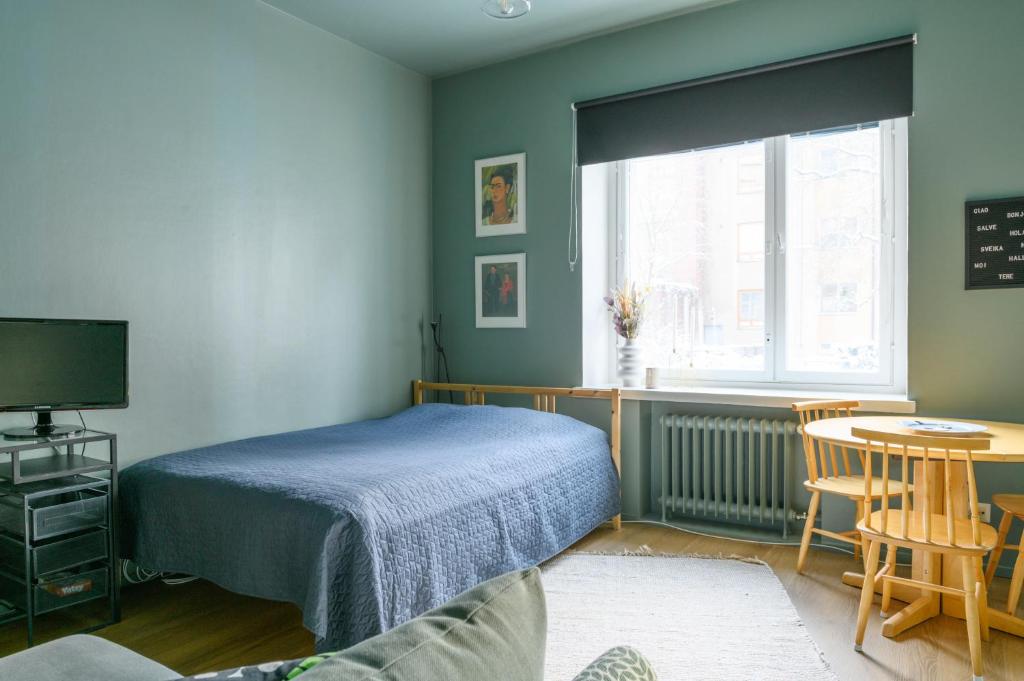 赫爾辛基的住宿－Hip studio near Central Park and City Center，一间卧室配有一张床、一张桌子和一个窗户。