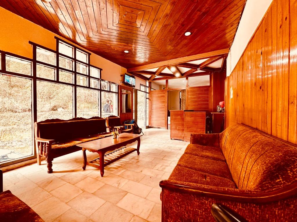 - un salon avec un canapé et une table dans l'établissement Hotel D Kanchan Manali, à Manali