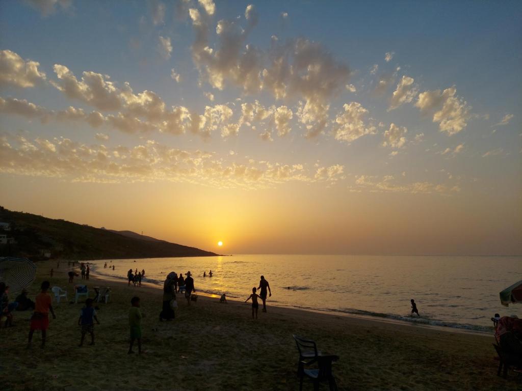 a group of people on the beach at sunset at Blue Horizon-Ghougine in Tangier