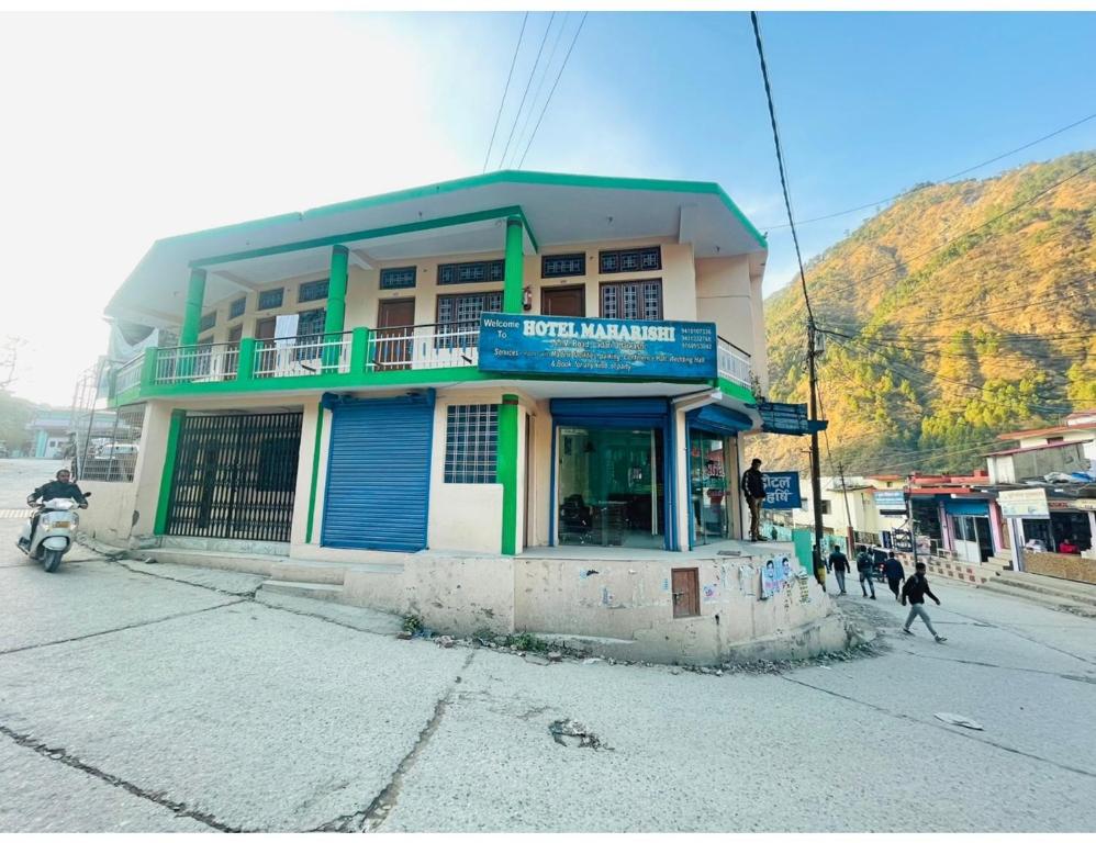 a building on the corner of a street with a man on a motorcycle at Hotel Maharishi, Uttarkashi in Uttarkāshi