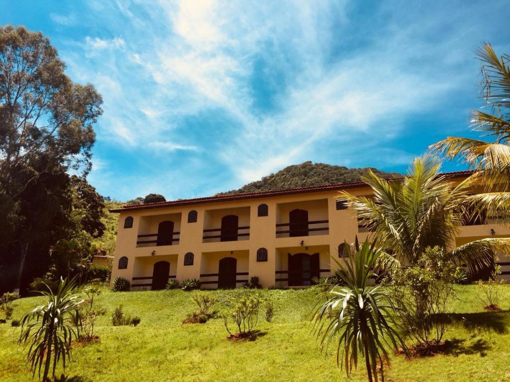 a building with palm trees in front of it at Hotel Fazenda Colina in Ouro Fino