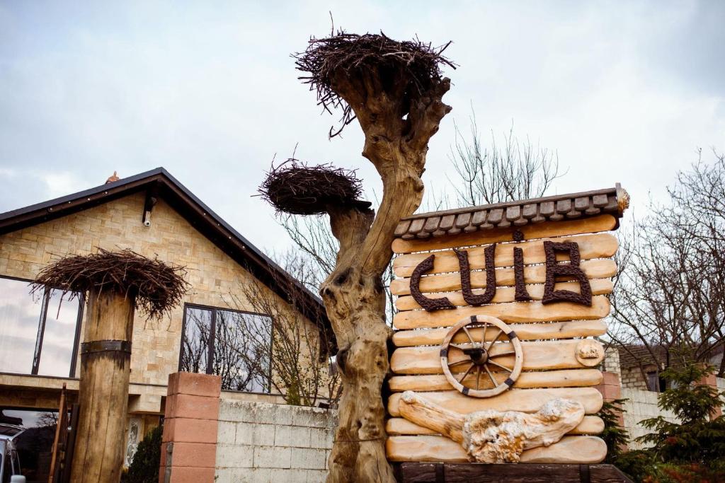 a building with a tree in front of a house at Cuib Complex Turistic in Căpriana