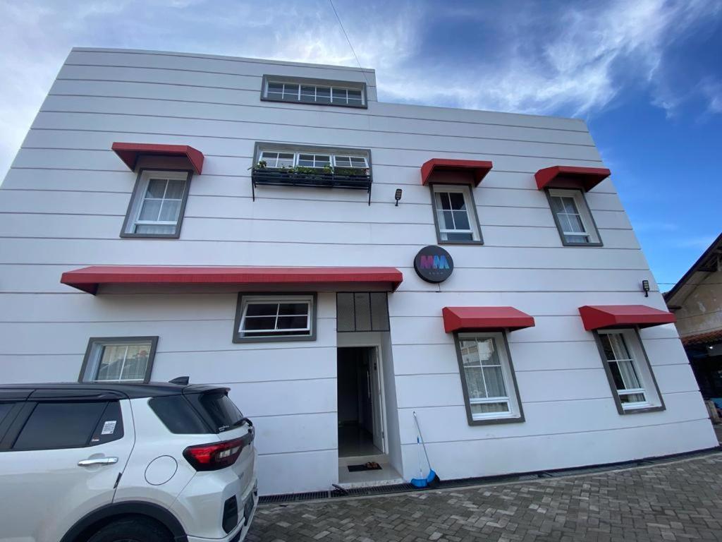 a white building with red a car parked in front of it at M&M'S ROOM in Lembang