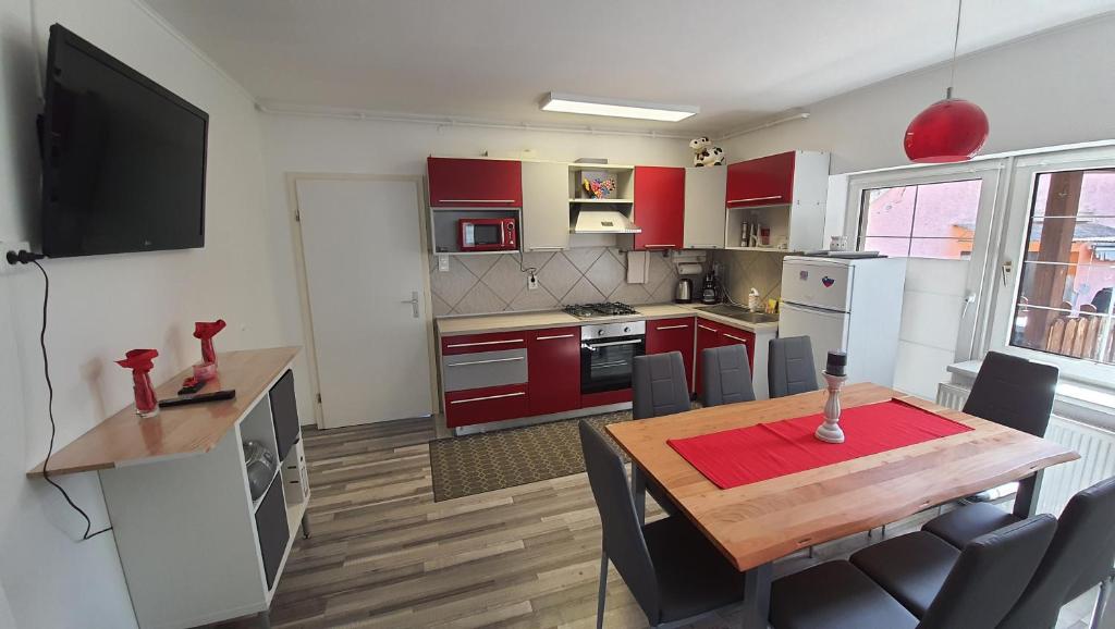 a kitchen with red cabinets and a wooden table with chairs at Apartma4us in Maribor