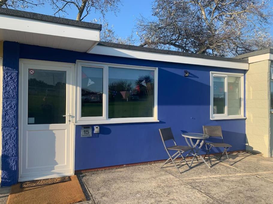 ein blaues Haus mit 2 Stühlen und einem Tisch in der Unterkunft “BLISS ON THE BAY ” chalet in Sandown Bay Holiday Park in Sandown