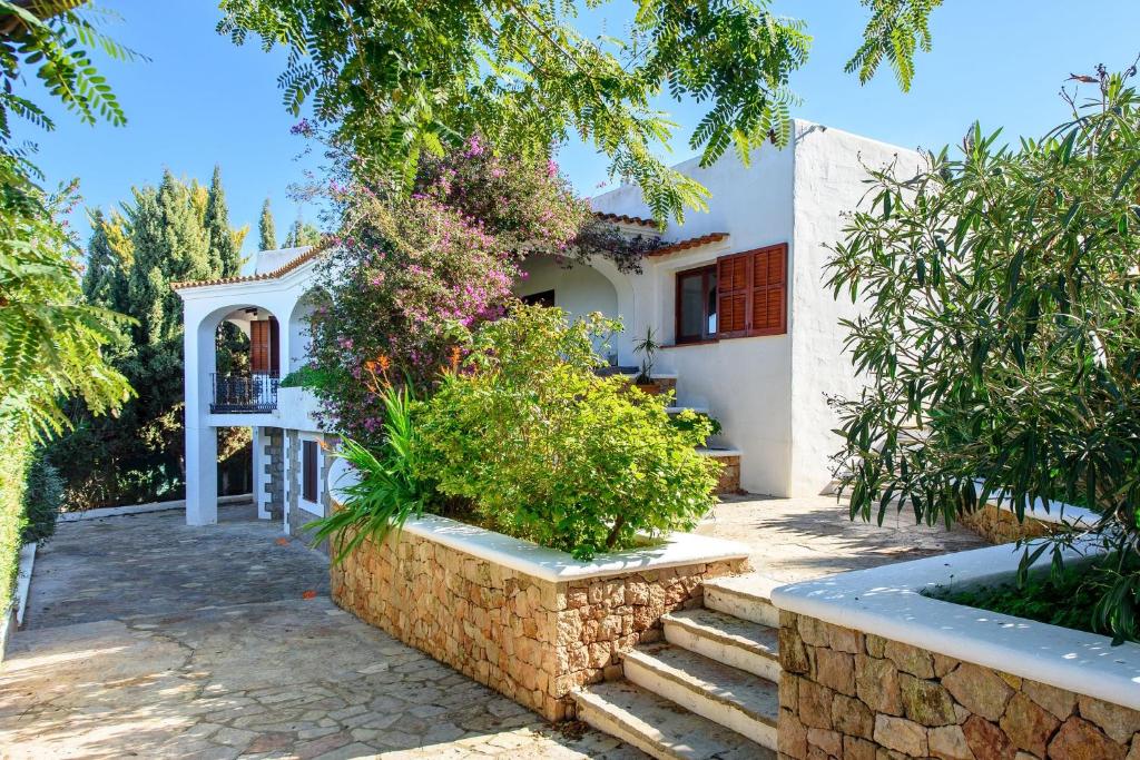 a white house with a stone wall and trees at Can Peppe in Sant Josep de Sa Talaia