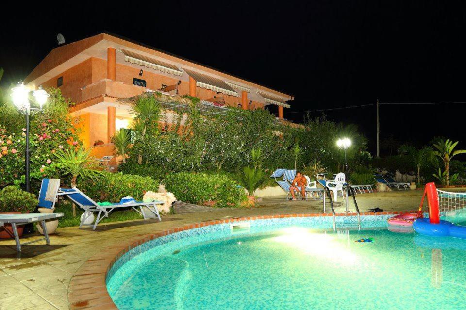 a swimming pool in front of a house at night at Agriturismo Brace in Santa Domenica