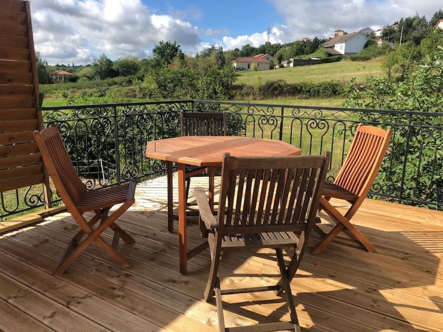 a wooden table and two chairs on a deck at Charmant studio neuf tout équipé terrasse vue imprenable, parking facile gratuit in Lézigneux