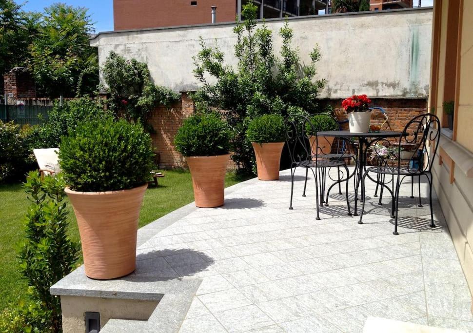 um pátio com uma mesa, cadeiras e vasos de plantas em Casa indipendente con giardino in città em Turim