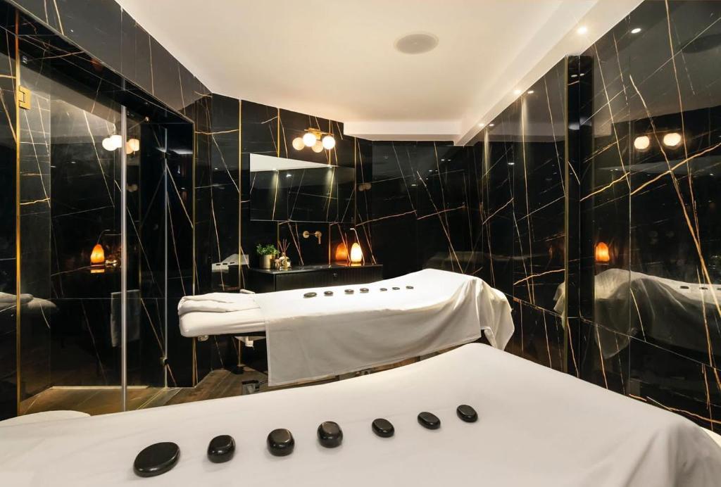 een zwart betegelde badkamer met een bad en een spiegel bij Beachfront Hotel: Pool, Spa, wet/dry Sauna & Gym in Ashkelon