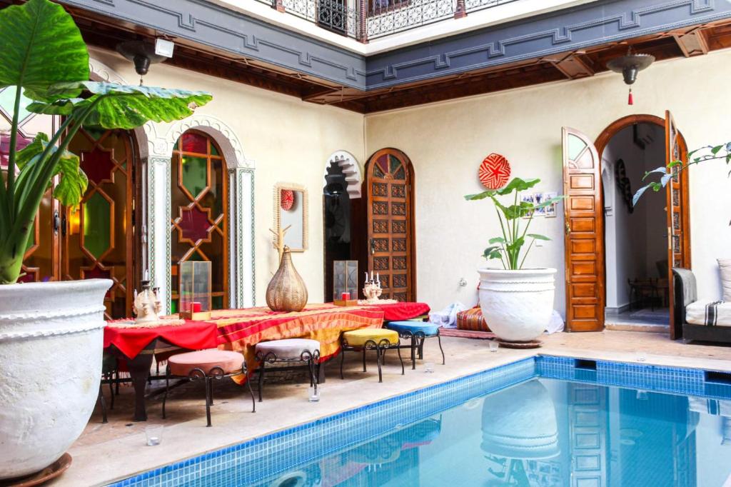 a patio with a table and chairs next to a swimming pool at RIAD KECHMARA in Marrakesh