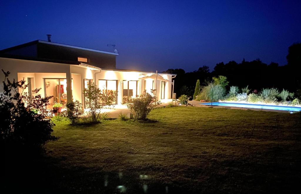 a house with lights on in a yard at night at Villa contemporaine avec piscine sur 4000 m2 à Rodez 9 personnes in Onet le Château