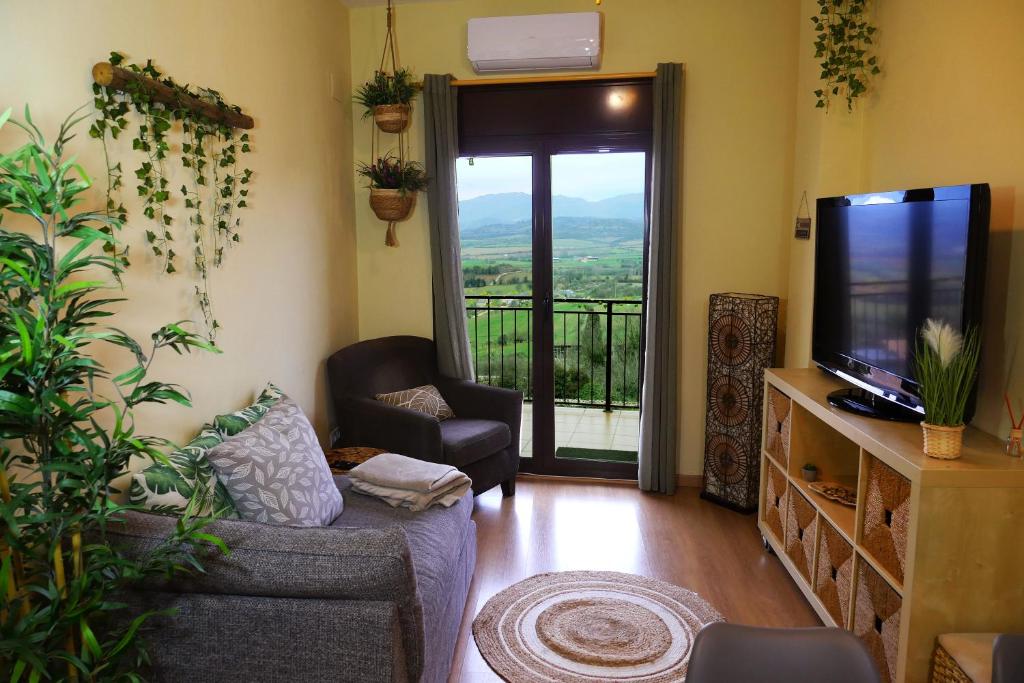 uma sala de estar com um sofá, uma televisão e uma varanda em Grace, apartamento con terraza y vistas em Talarn