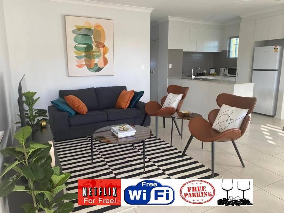 uma sala de estar com um sofá azul e cadeiras em Stylish 2Bed Close Airport/Shops em Perth
