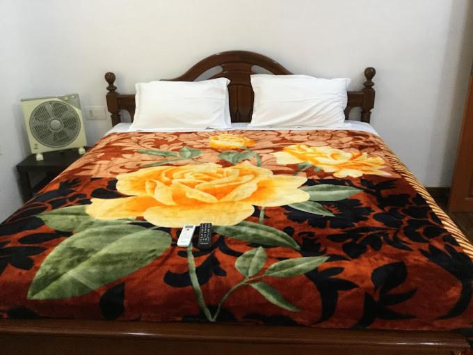 łóżko z kocem z żółtymi kwiatami w obiekcie Villa Serenity Le Sejour Pondicherry w mieście Kottakupam