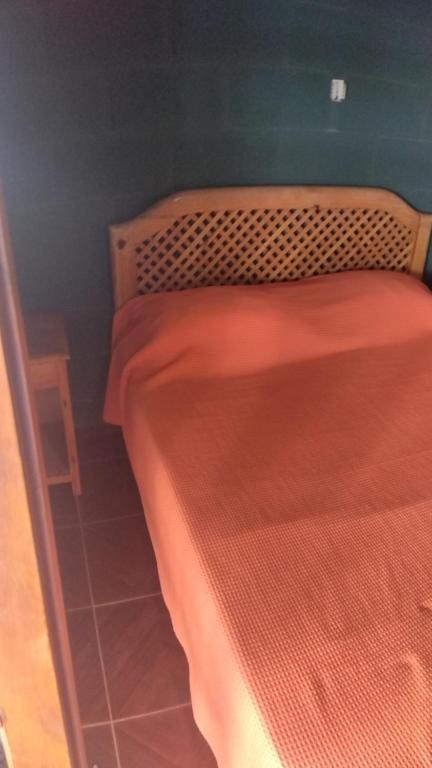 1 dormitorio con cama de madera con sábanas rojas en Pecas house en Mina Clavero