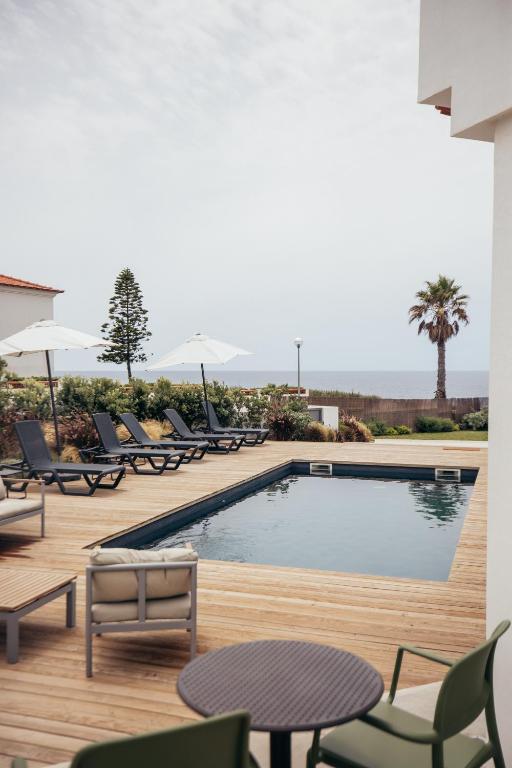 a swimming pool with chairs and a table and a pool at MUTE Hostel Porto Covo in Porto Covo