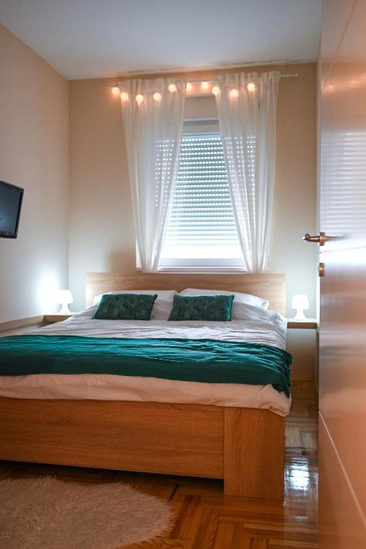 a bedroom with a large bed with a window at Lena Apartman in Subotica