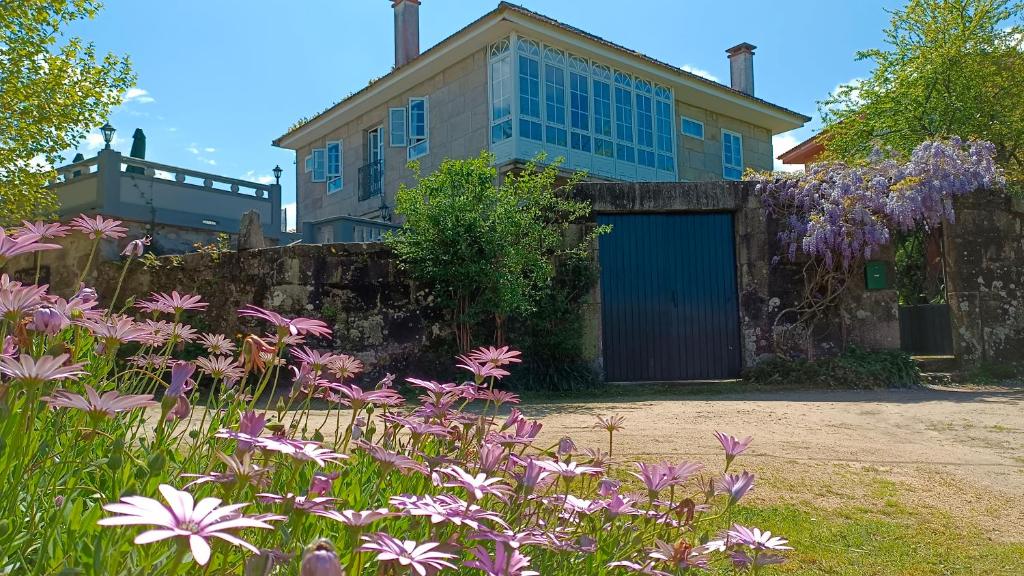 una casa con un garage blu e fiori viola di Casa Estarque a Gondomar