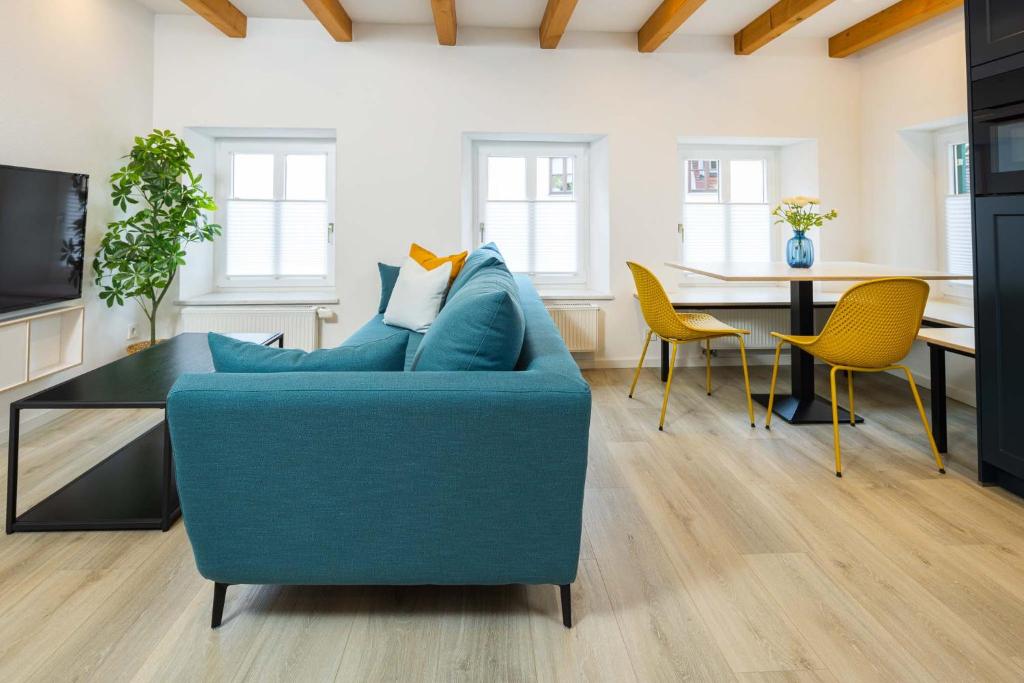 a living room with a blue couch and chairs at Stadtmauer-Apartments - Stilvolle Wohnung mit King Bett direkt an der historischen Stadtmauer in Nördlingen