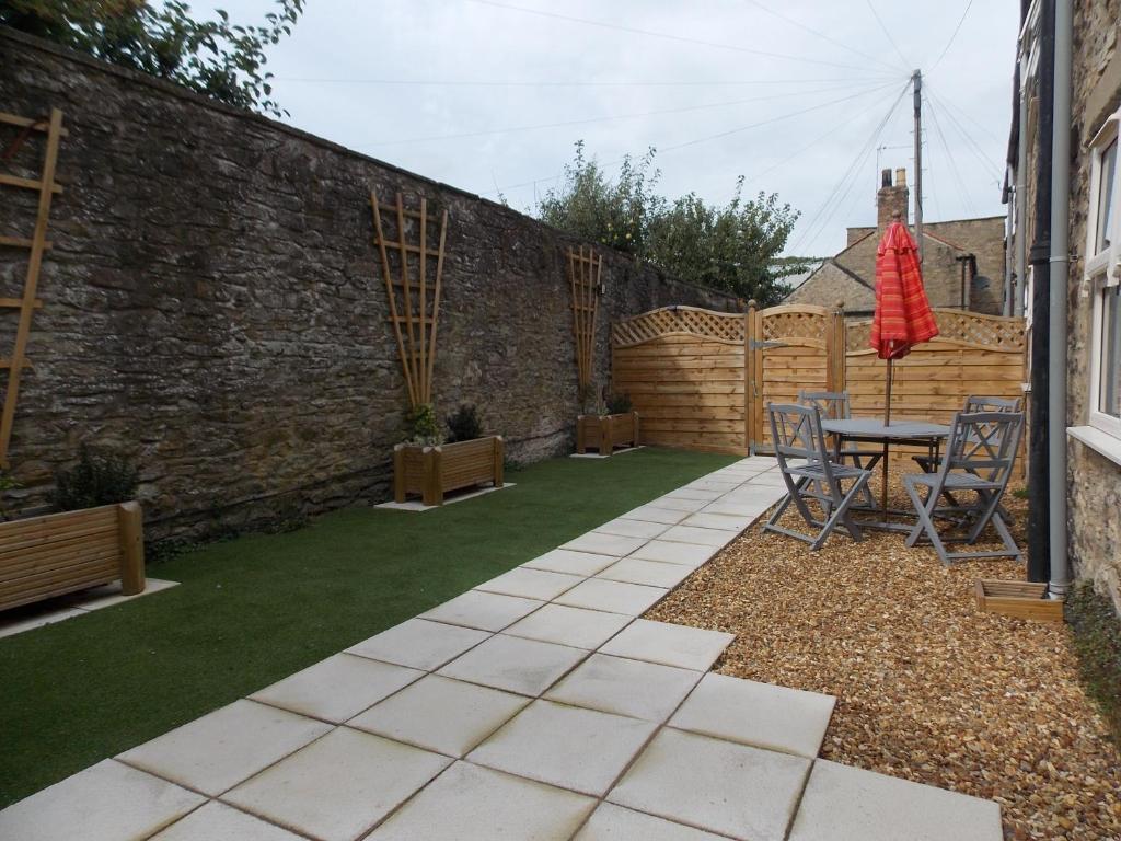 a garden with a table and chairs next to a brick wall at Fryers Cottage in Richmond