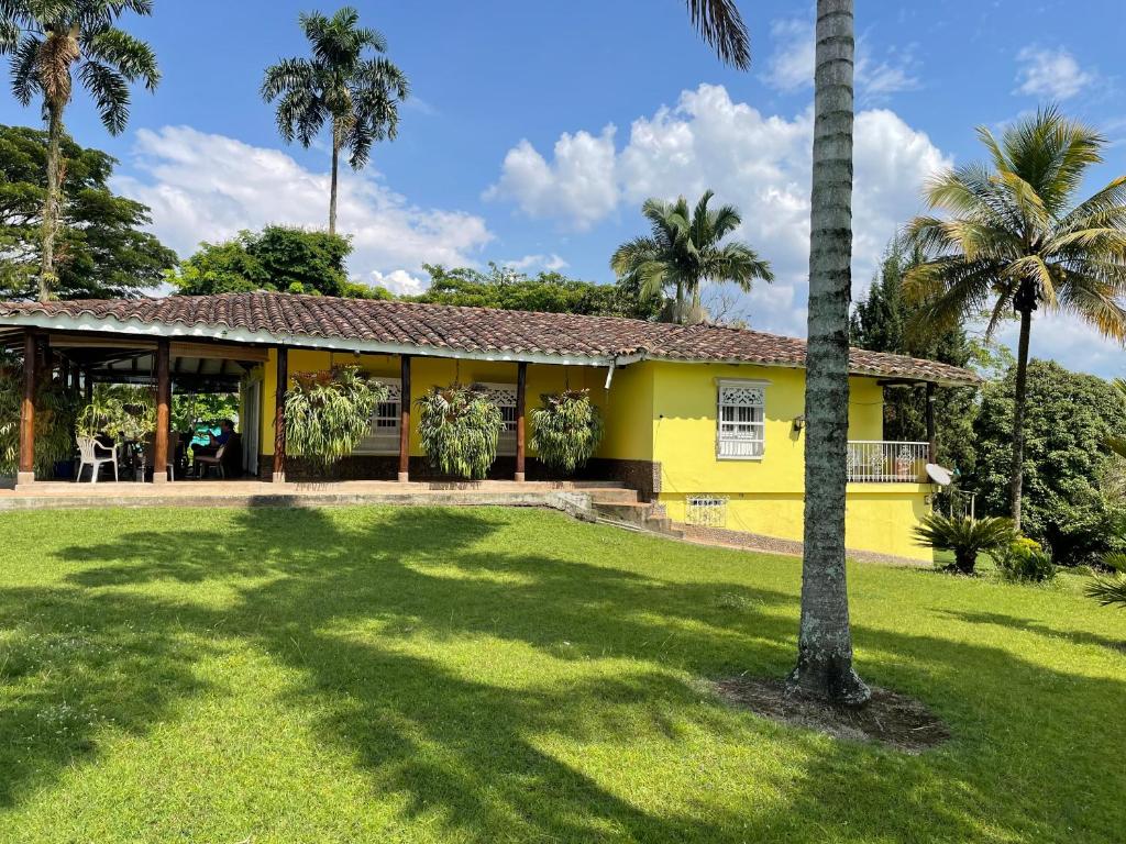 a yellow house with a palm tree in the yard at Finca El Cortijo Pereira in Pereira