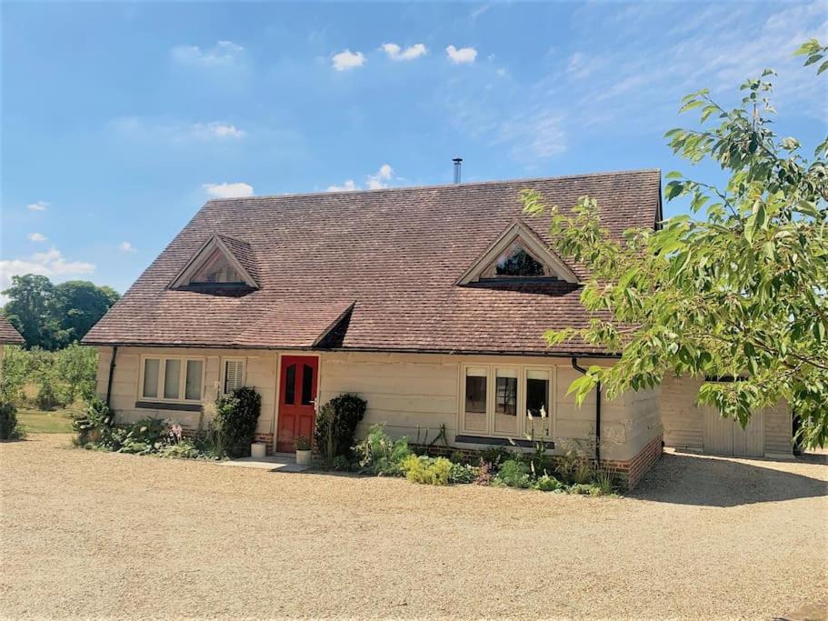 a white house with a red door and a driveway at Meadow Cottage in Hampshire's Test Valley in Andover