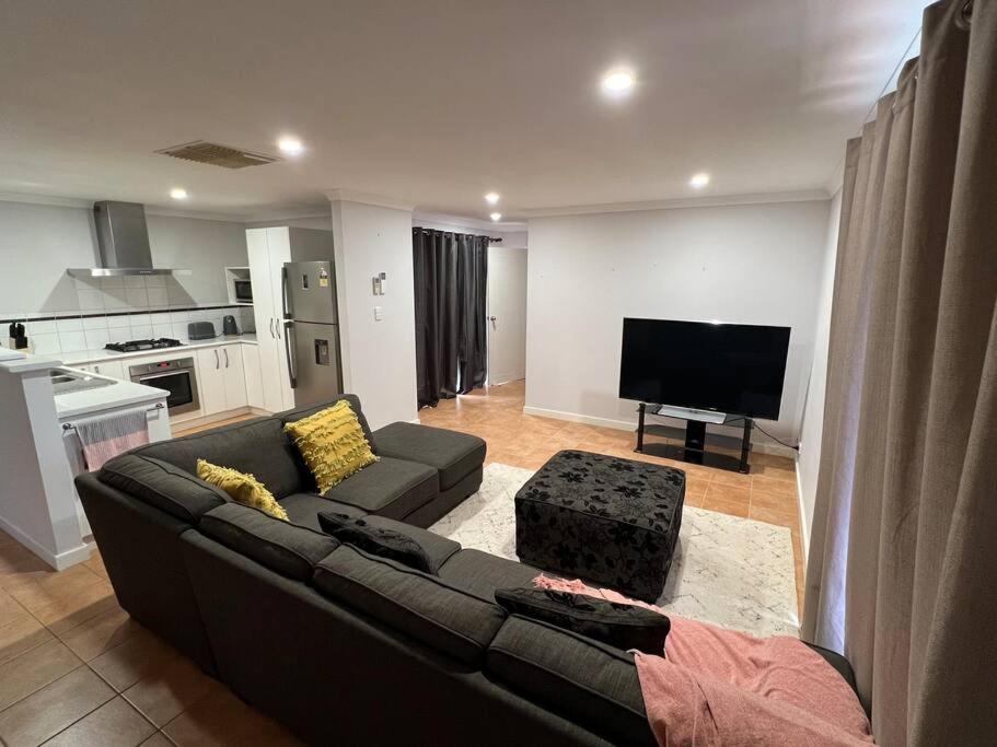 a living room with a couch and a flat screen tv at Free secure parking & WiFi in this Executive 3 BR. in Kalgoorlie