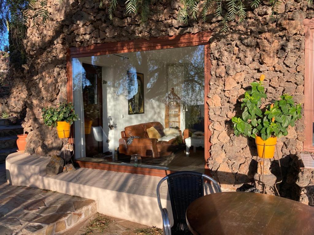 a room with a stone wall with a couch and a table at Apartamento Pirul in Haría