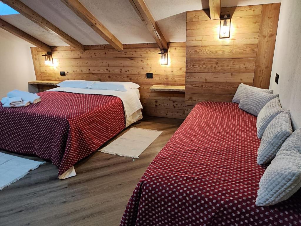 two beds in a room with wooden walls at A casa da Elide in Aymavilles