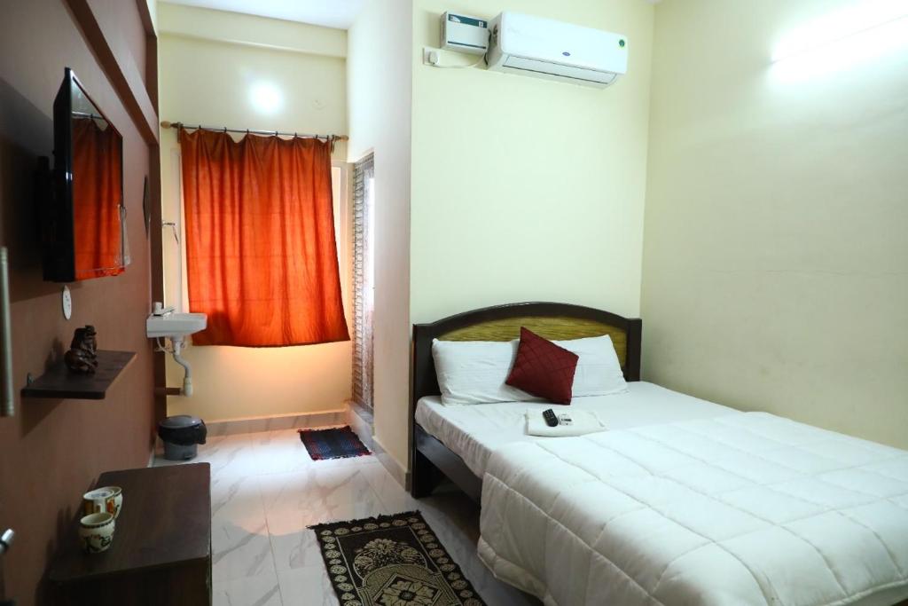 a bedroom with a white bed with a red curtain at Babu Naidu Residency in Vellore