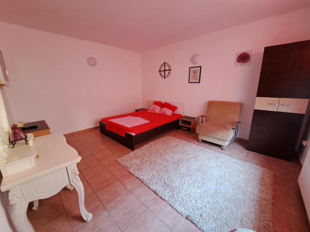 a bedroom with a red bed and a chair at Apartament un dormitor și living la curte Corbu in Corbu