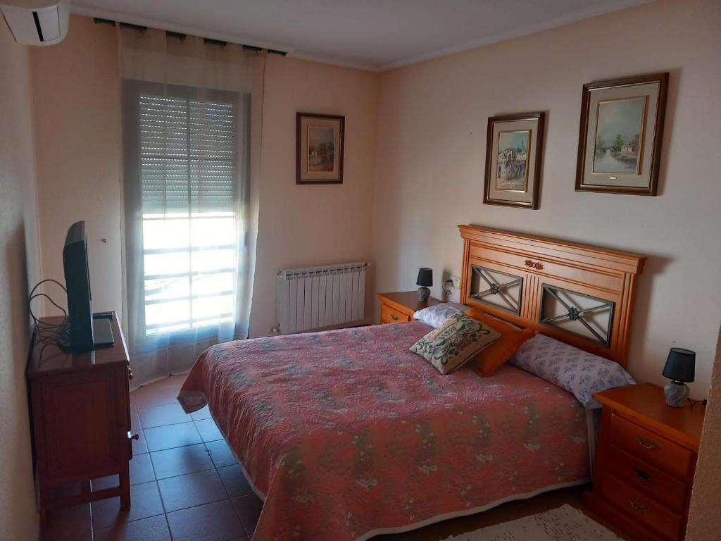 Schlafzimmer mit einem Bett, einem TV und einem Fenster in der Unterkunft Casa Rosangela in Almonacid de Toledo