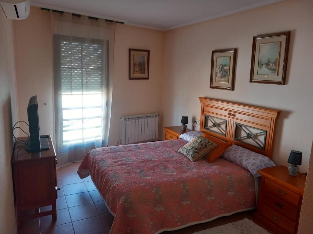 1 dormitorio con 1 cama, TV y ventana en Casa Rosangela, en Almonacid de Toledo