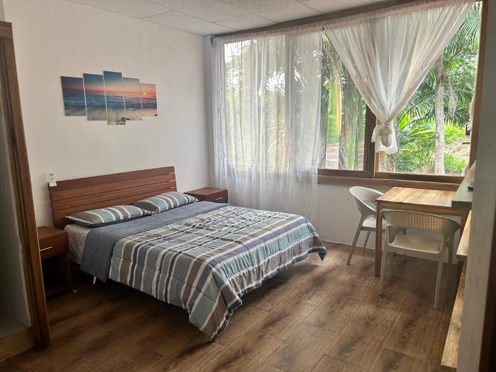 a bedroom with a bed and a desk and a window at ROOM COLIBRÍ - La Casa de Eros in Ayampe