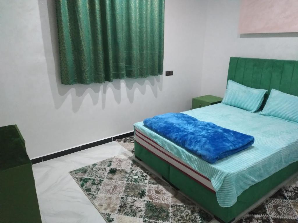 ein Schlafzimmer mit einem Bett mit blauen Kissen und einem Gemälde in der Unterkunft إقامة الخيمة للشقق المفروشة in El Aaiún