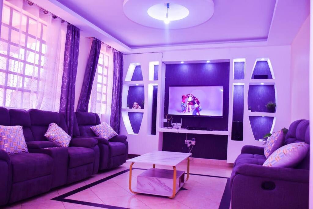 a living room with purple couches and a tv at Serenity Home in Lake View Estate