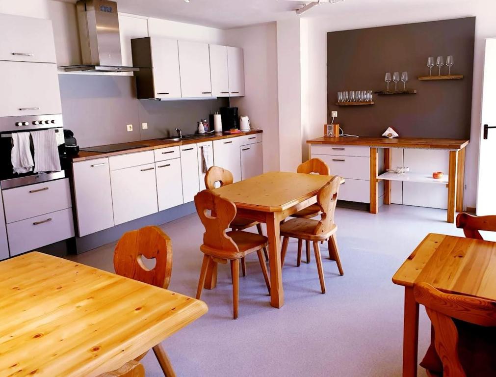 una cocina con armarios blancos y mesas y sillas de madera. en Weingut Krell, en Mitterretzbach