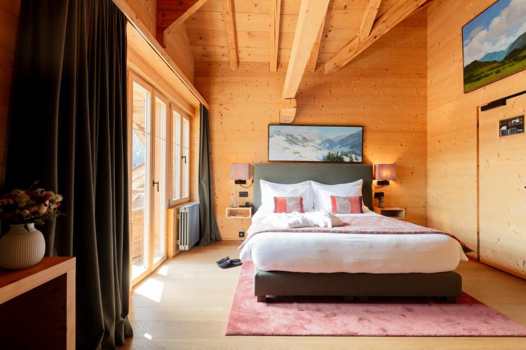 a bedroom with a bed and a large window at Hotel-Restaurant Valrose in Gstaad