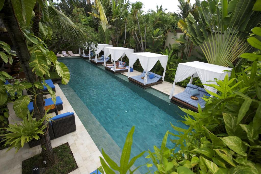 
a swimming pool filled with lots of green umbrellas at The Elysian Boutique Villa Hotel in Seminyak
