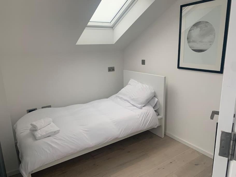 a white bed in a room with a window at Dockside Sleeps 8, Uber Boat to Canary Wharf in 3 mins in London