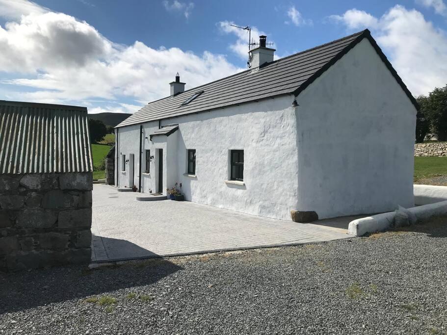 a small white building with a driveway in front of it at Mournes Family Cottage with Hot Tub in Hilltown