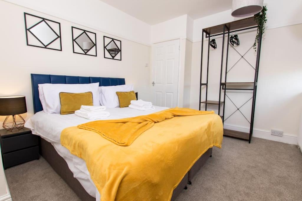 a bedroom with a large bed with a yellow blanket on it at Spacious-Comfortable-Free Parking-Garden in Nottingham