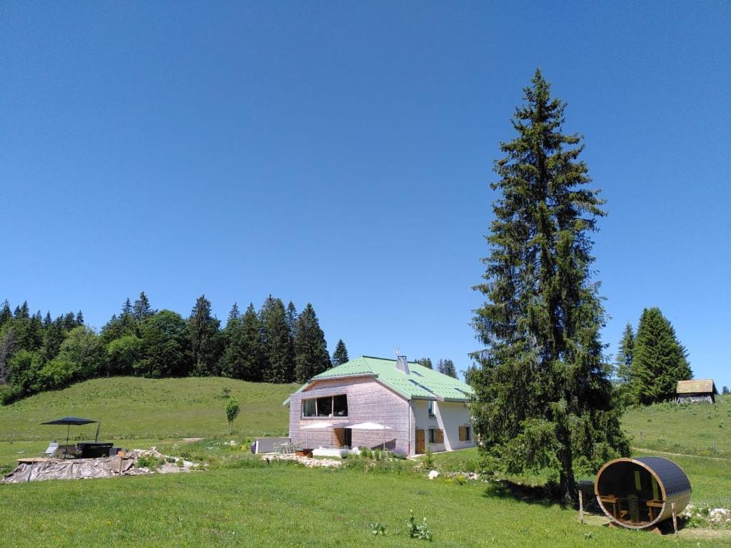 una casa rosa in un campo con un albero di La Ferme du Lanchet a Lamoura